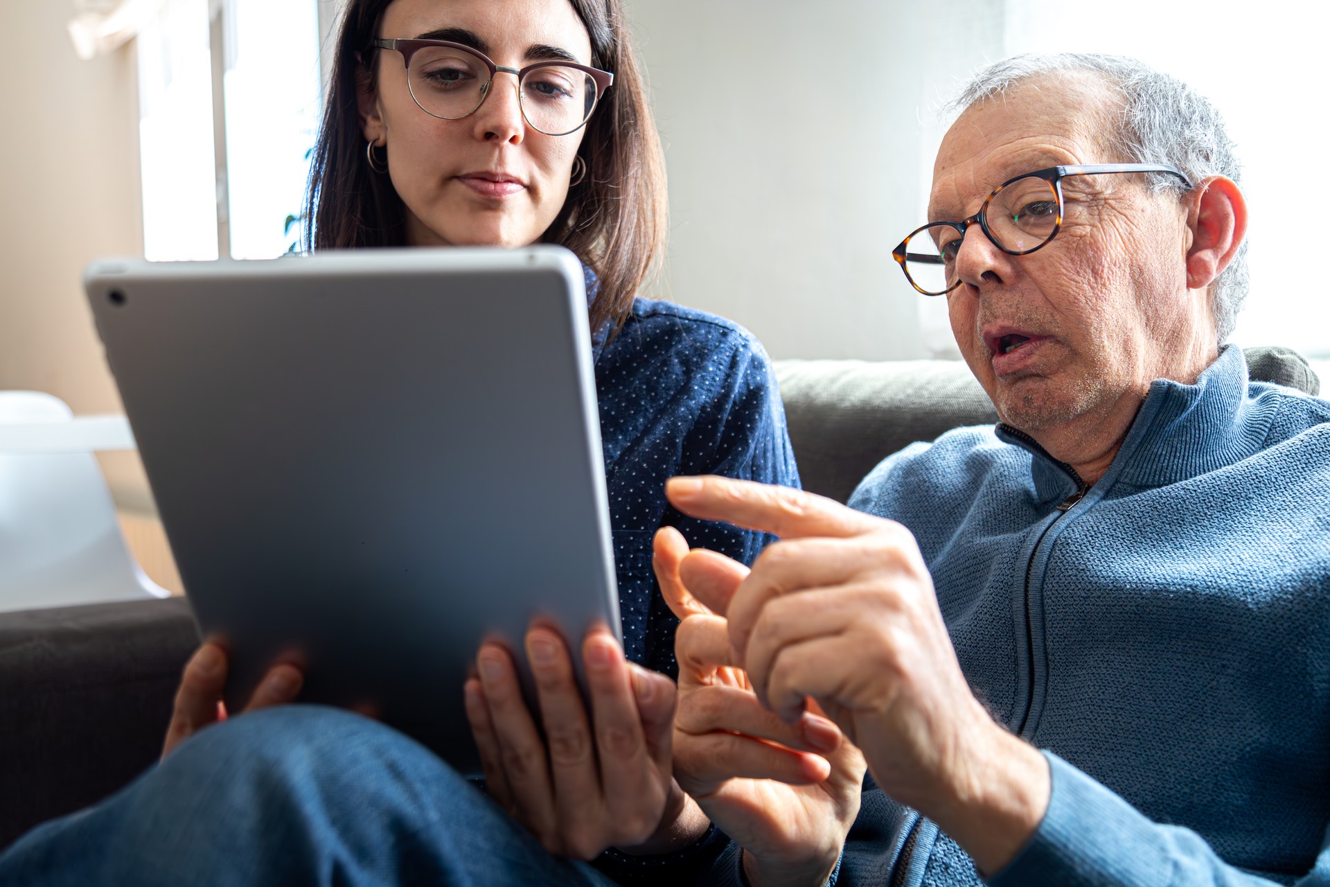 Senior man explaining to his young daughter with help of digital tablet.