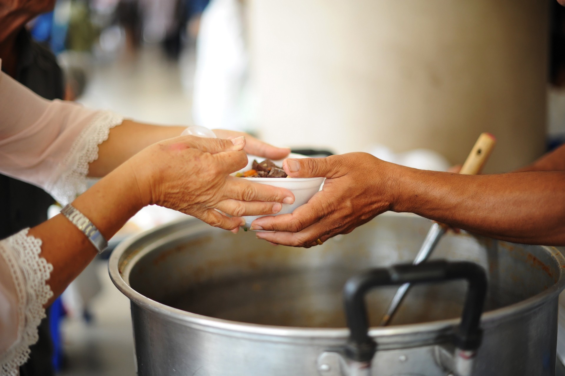 Volunteers provide food for beggars : Concepts Feeding and help : The hands of the rich give food to the hands of the poor